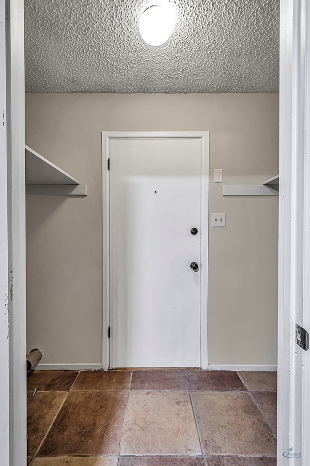 interior space with stone finish flooring, baseboards, and a textured ceiling