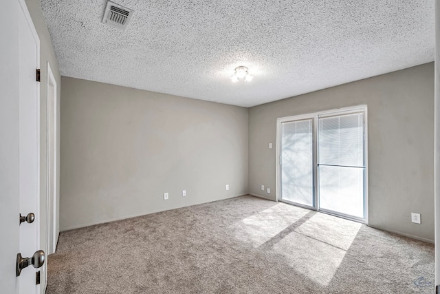 carpeted spare room with visible vents and a textured ceiling