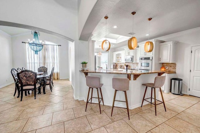 10104 E County Rd 103, Midland, TX 79706 - kitchen featuring a chandelier, appliances with stainless steel finishes, a breakfast bar area, recessed lighting, and crown molding