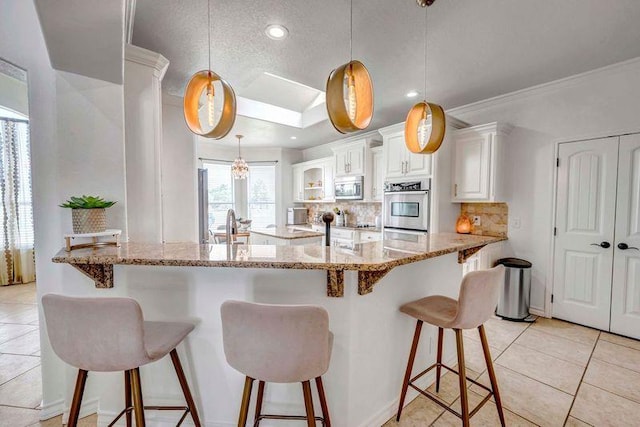 10104 E County Rd 103, Midland, TX 79706 - kitchen with stainless steel microwave, backsplash, a kitchen breakfast bar, white cabinets, and light stone counters