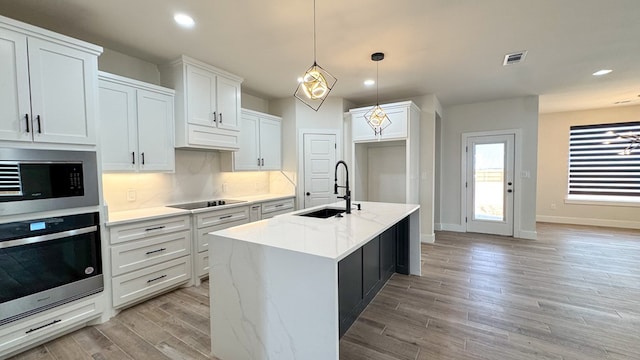 13223 E County Rd 110, Midland, TX 79706 - kitchen featuring oven, built in microwave, a sink, black electric stovetop, and light wood-style floors