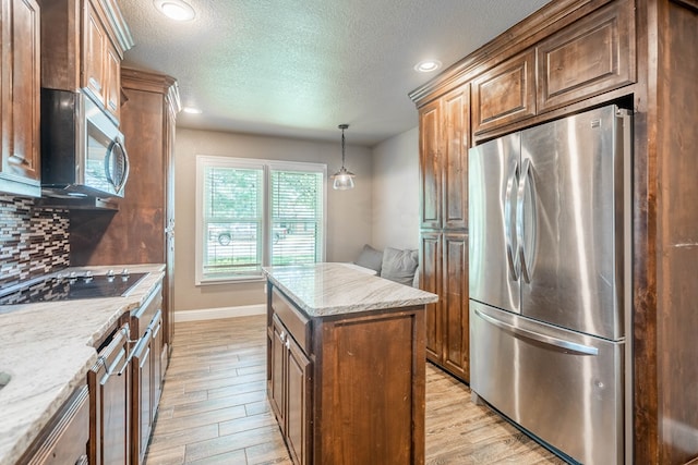 2205 Boyd Ave, Midland, TX 79705 - kitchen with stainless steel appliances, a center island, a textured ceiling, light wood-style floors, and tasteful backsplash