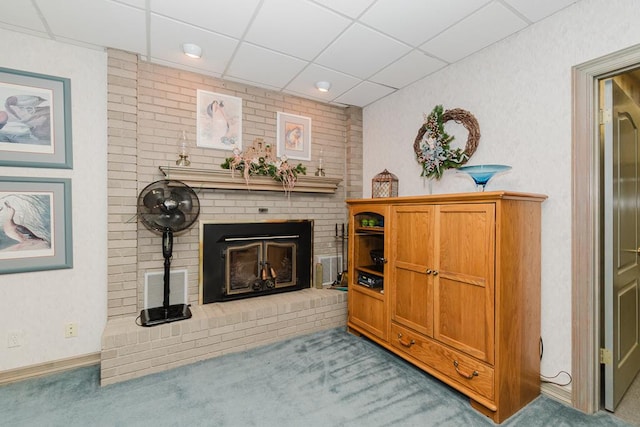 interior space with carpet floors, a drop ceiling, and a brick fireplace