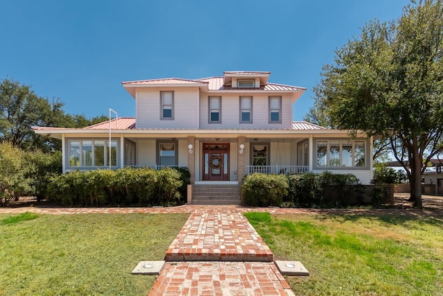 view of front of home featuring metal roof, a porch, and a front yard