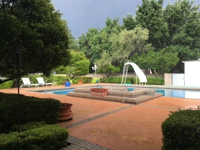 outdoor pool with a patio, a water slide, and a jacuzzi