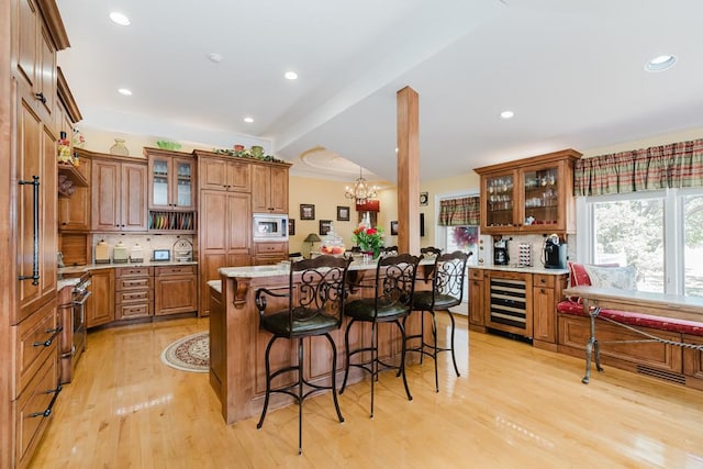 kitchen with beverage cooler, appliances with stainless steel finishes, brown cabinetry, and a kitchen bar