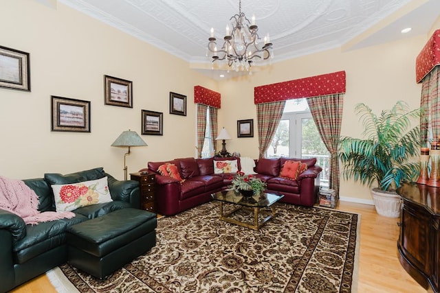 living room with crown molding, a notable chandelier, baseboards, and wood finished floors