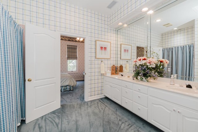 ensuite bathroom with double vanity, connected bathroom, visible vents, and a sink