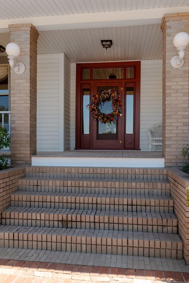 entrance to property with a porch and brick siding