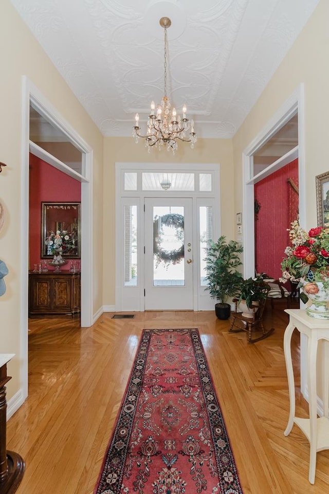 foyer entrance with a notable chandelier, light wood finished floors, and baseboards