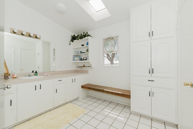 bathroom with lofted ceiling with skylight, vanity, and tile patterned floors