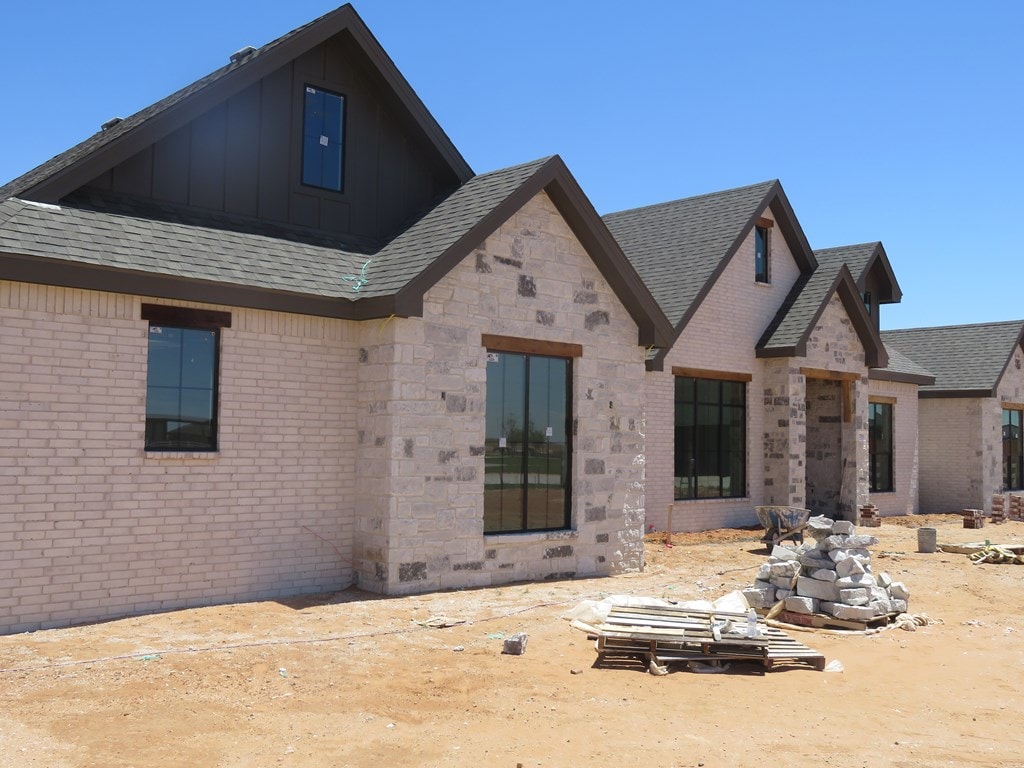 2701 S County Rd 1092, Midland, TX 79706 - back of house with brick siding, board and batten siding, and roof with shingles