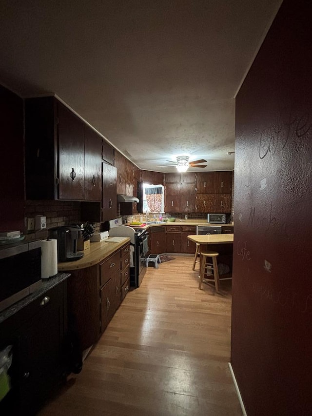 3103 Hill Ave, Snyder, TX 79549 - kitchen with black gas range, light wood finished floors, light countertops, stainless steel microwave, and a ceiling fan