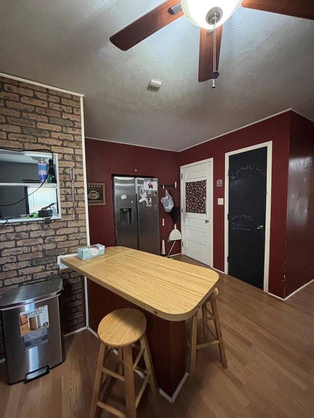3103 Hill Ave, Snyder, TX 79549 - kitchen with stainless steel fridge with ice dispenser, a ceiling fan, wood finished floors, butcher block counters, and a breakfast bar