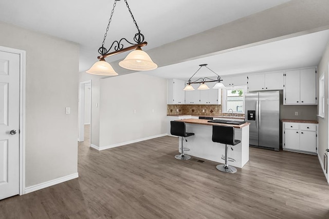 306 S Moss Lake Rd, Big Spring, TX 79720 - kitchen featuring stainless steel refrigerator with ice dispenser, dark wood-style flooring, a kitchen island, and white cabinetry
