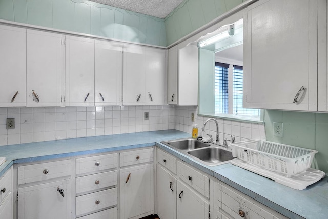 2502 Ann Dr, Big Spring, TX 79720 - kitchen featuring a sink, white cabinets, light countertops, backsplash, and a textured ceiling