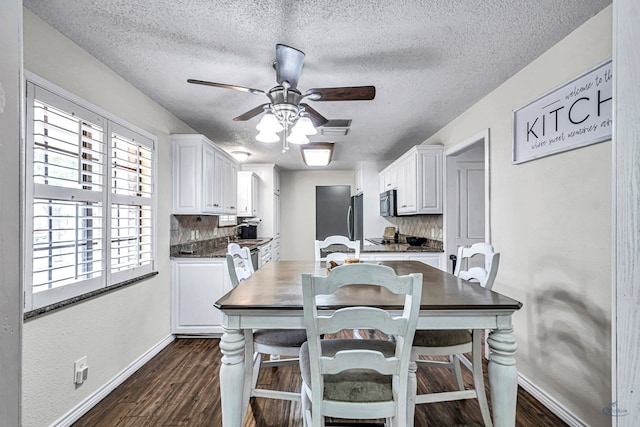kitchen featuring dark countertops, ceiling fan, a textured ceiling, white cabinetry, and baseboards