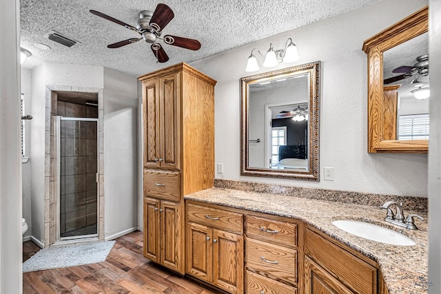 full bath featuring visible vents, wood finished floors, ceiling fan, a textured ceiling, and a shower stall