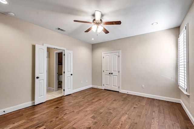 unfurnished bedroom featuring ceiling fan, multiple windows, and light hardwood / wood-style flooring