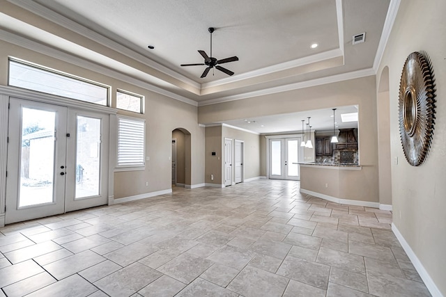 unfurnished living room featuring a tray ceiling, ornamental molding, french doors, and ceiling fan