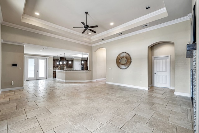 unfurnished living room featuring crown molding, ceiling fan, and a raised ceiling