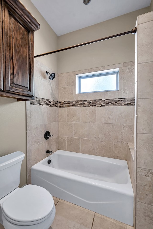 bathroom featuring tiled shower / bath, toilet, and tile patterned flooring