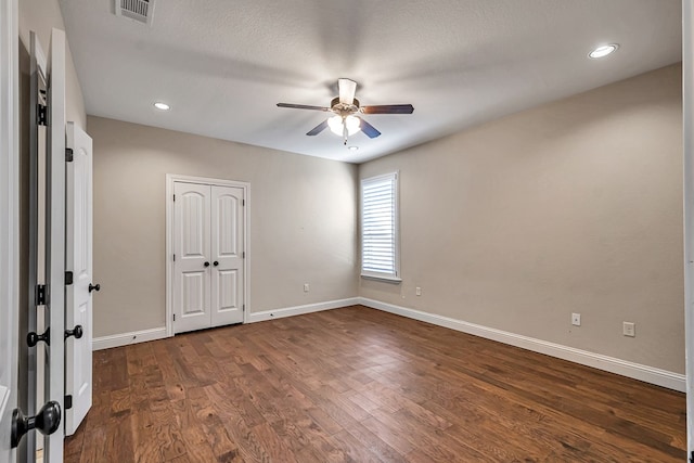 empty room with dark wood-type flooring, a textured ceiling, and ceiling fan