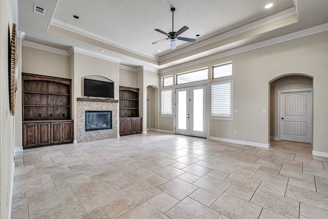 unfurnished living room featuring crown molding, a raised ceiling, ceiling fan, and french doors