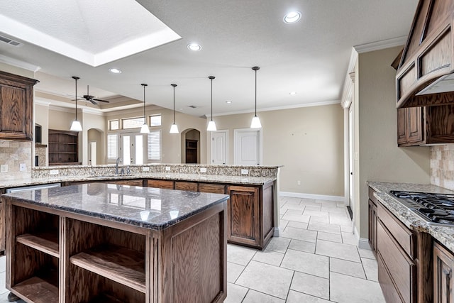 kitchen with hanging light fixtures, kitchen peninsula, dark stone counters, and a kitchen island