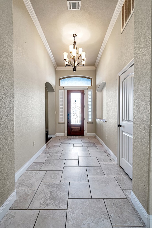 tiled entrance foyer with an inviting chandelier and ornamental molding