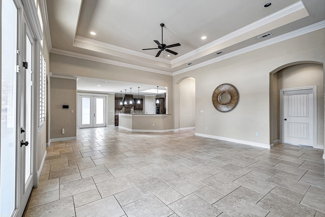 unfurnished living room with a raised ceiling, ceiling fan, and french doors