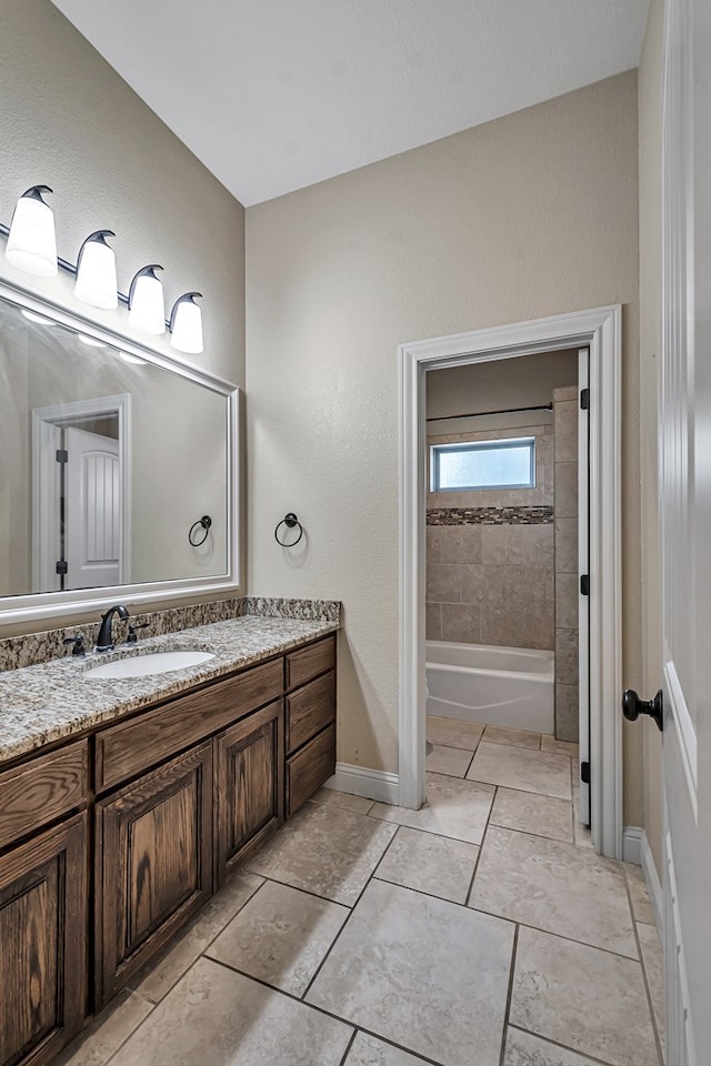 bathroom with tiled shower / bath combo, vanity, and tile patterned floors