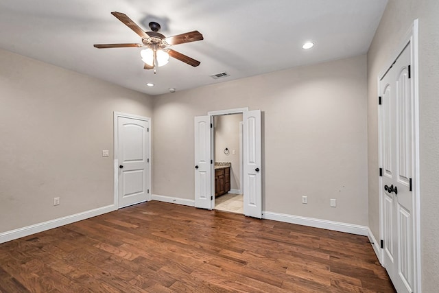 unfurnished bedroom with ensuite bath, wood-type flooring, and ceiling fan