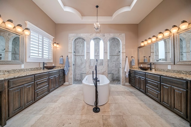 bathroom featuring a raised ceiling, separate shower and tub, vanity, and a chandelier