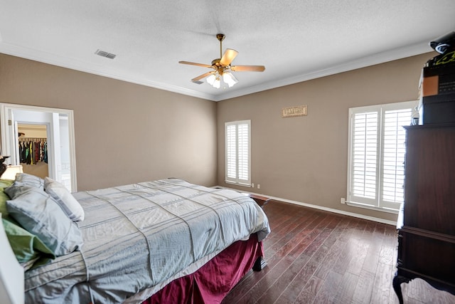 bedroom featuring dark wood-type flooring, ornamental molding, baseboards, a textured ceiling, and a ceiling fan