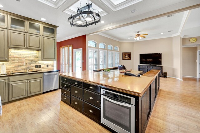 5810 Sterling Pl, Midland, TX 79707 - kitchen with appliances with stainless steel finishes, a sink, light wood finished floors, ornamental molding, and decorative backsplash