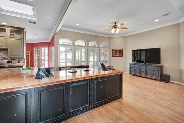 5810 Sterling Pl, Midland, TX 79707 - kitchen featuring light wood-style floors, ceiling fan, dark cabinetry, crown molding, and backsplash