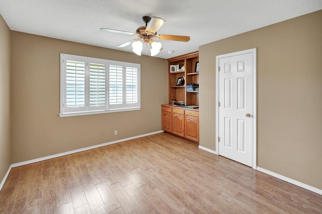 unfurnished bedroom featuring light wood-type flooring, baseboards, and a ceiling fan