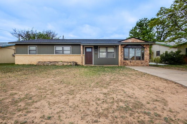 ranch-style home featuring a front lawn, driveway, a shingled roof, and brick siding
