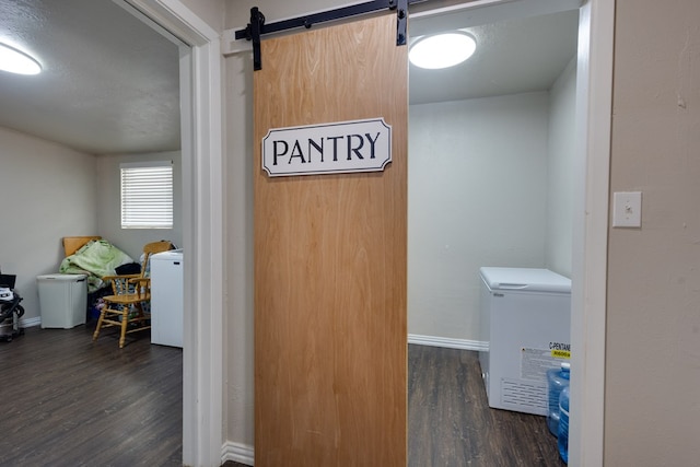 laundry area featuring wood finished floors, a barn door, laundry area, and baseboards
