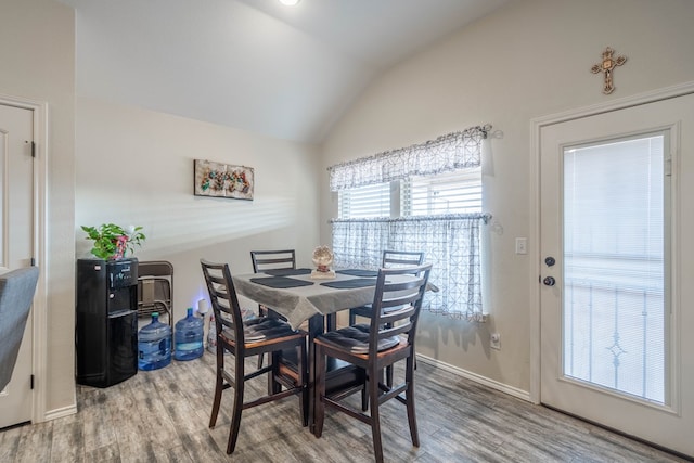 dining room with vaulted ceiling and wood-type flooring