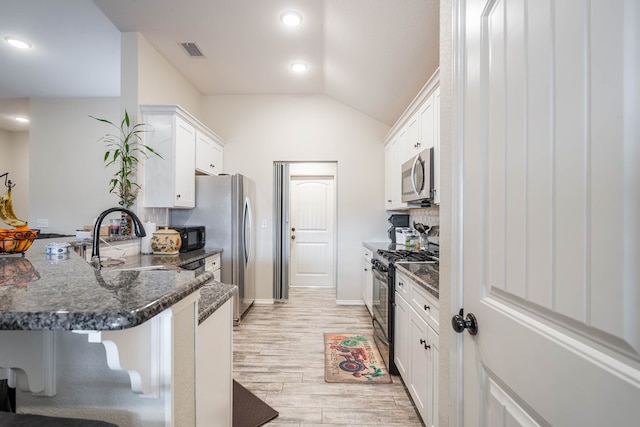 kitchen with light hardwood / wood-style flooring, a breakfast bar, stainless steel appliances, white cabinets, and kitchen peninsula