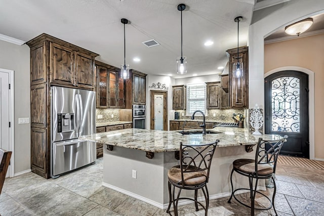 kitchen featuring a sink, visible vents, light stone counters, arched walkways, and appliances with stainless steel finishes