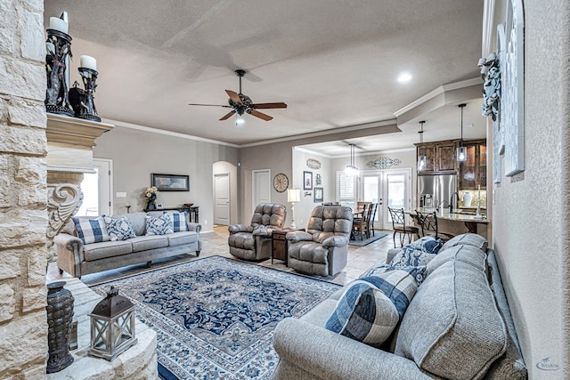 living room featuring recessed lighting, arched walkways, ceiling fan, a textured ceiling, and crown molding
