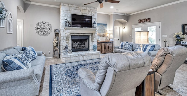 living area featuring a fireplace, crown molding, a ceiling fan, baseboards, and arched walkways
