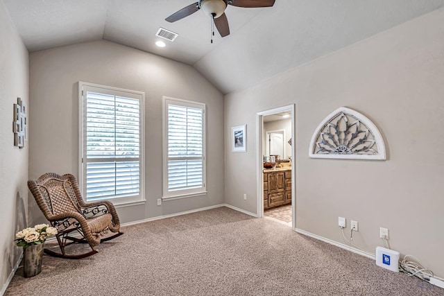 sitting room with lofted ceiling, light colored carpet, visible vents, baseboards, and a ceiling fan