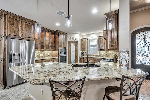 kitchen with a kitchen breakfast bar, a sink, appliances with stainless steel finishes, visible vents, and a peninsula