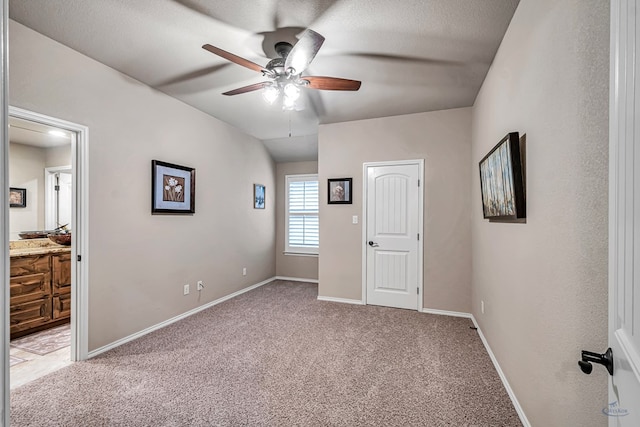 unfurnished bedroom featuring ensuite bathroom, ceiling fan, light colored carpet, and baseboards
