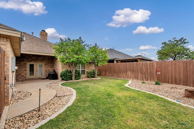 view of yard featuring french doors, a fenced backyard, and a patio area
