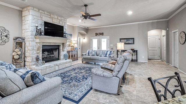 living room featuring stone tile floors, ceiling fan, baseboards, and arched walkways